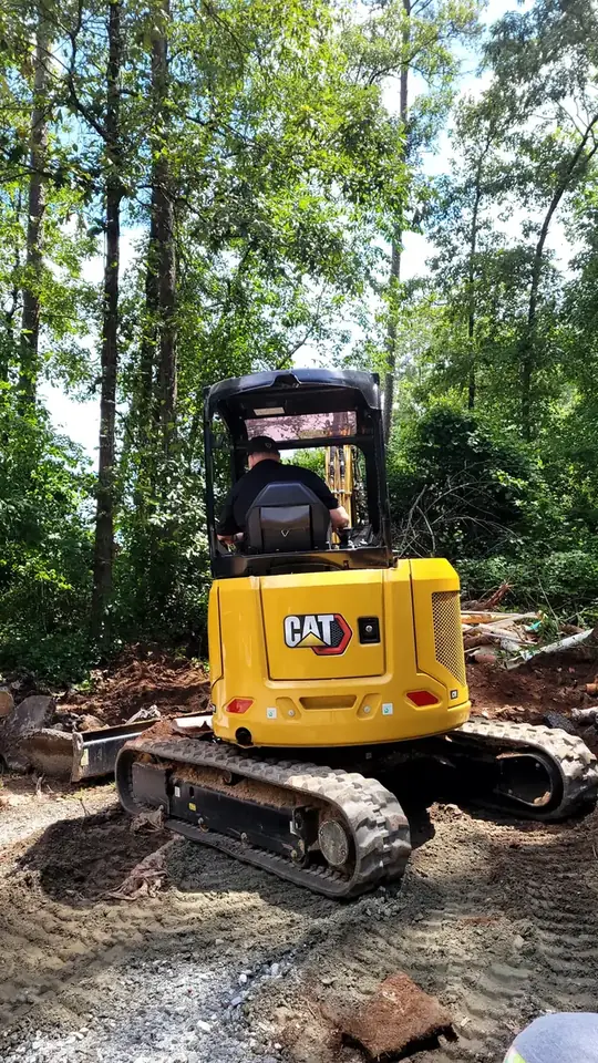 Mini excavator opening ground beside a house for a buried line