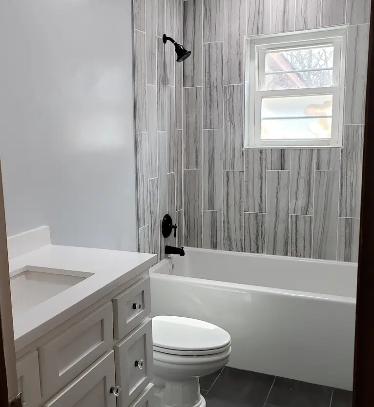 Finished bathroom with tiled tub surround and a new vanity