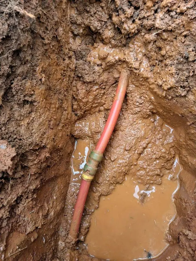 Excavated copper water line with a repair coupling fitted in the trench