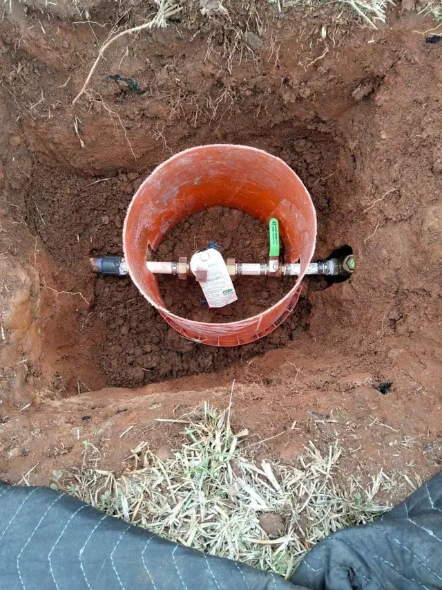 Water meter and valve box exposed in an excavated pit